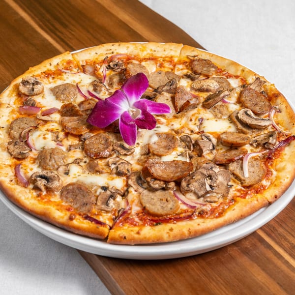 Mona Lisa Cucina's sausage, mushroom, and red onion pizza, garnished with a purple orchid.