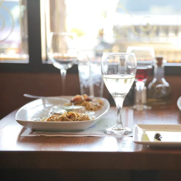 Italian pasta dish with white wine and olive oil on a wooden table.