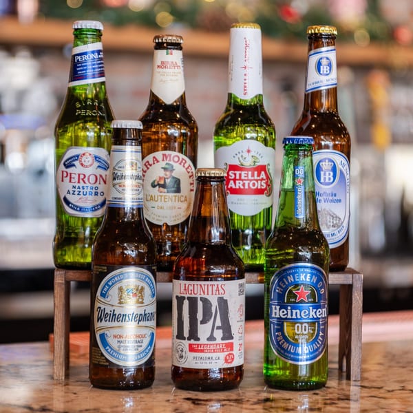 A variety of Italian and international beer bottles, including Peroni and Moretti, displayed on a bar.