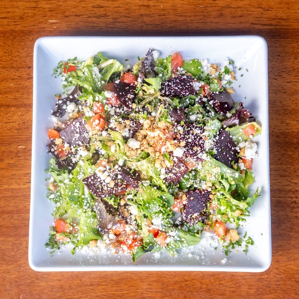 Overhead view of a Mona Lisa Cucina salad with mixed greens, tomatoes, cheese, and croutons.
