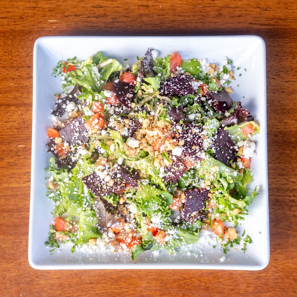 Overhead view of a Mona Lisa Cucina salad with mixed greens, tomatoes, cheese, and croutons.