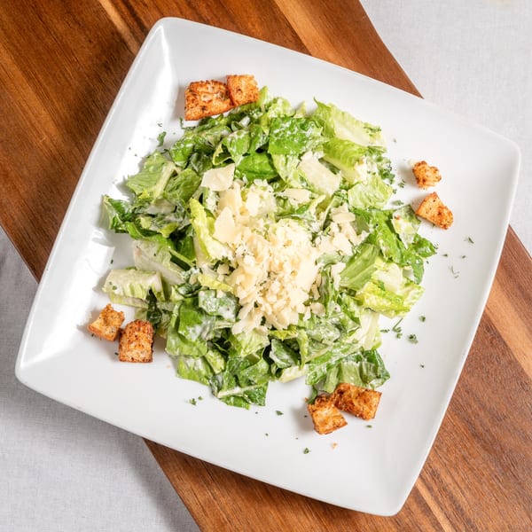 A Mona Lisa Cucina Caesar salad with romaine lettuce, creamy dressing, croutons, and Parmesan cheese.