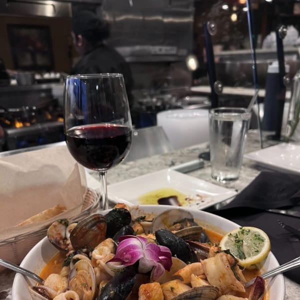 Mona Lisa Cucina's seafood pasta with clams, mussels, and squid, garnished with a purple orchid.