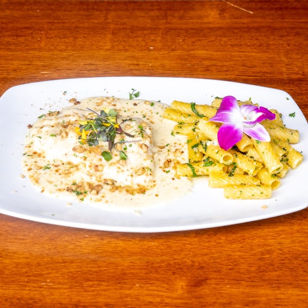Mona Lisa Cucina's creamy chicken dish with rigatoni pasta, garnished with a purple orchid.
