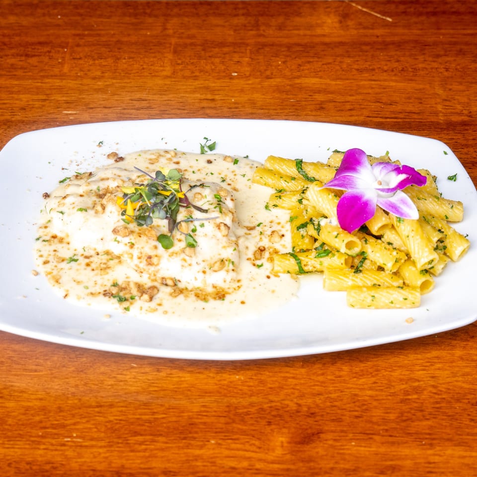 Mona Lisa Cucina's creamy chicken dish with rigatoni pasta, garnished with a purple orchid.
