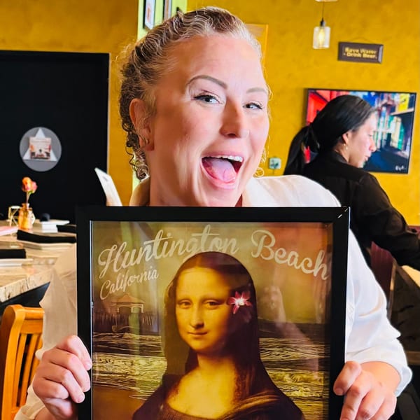 A woman excitedly holds a framed picture of Mona Lisa with a flower in her hair.